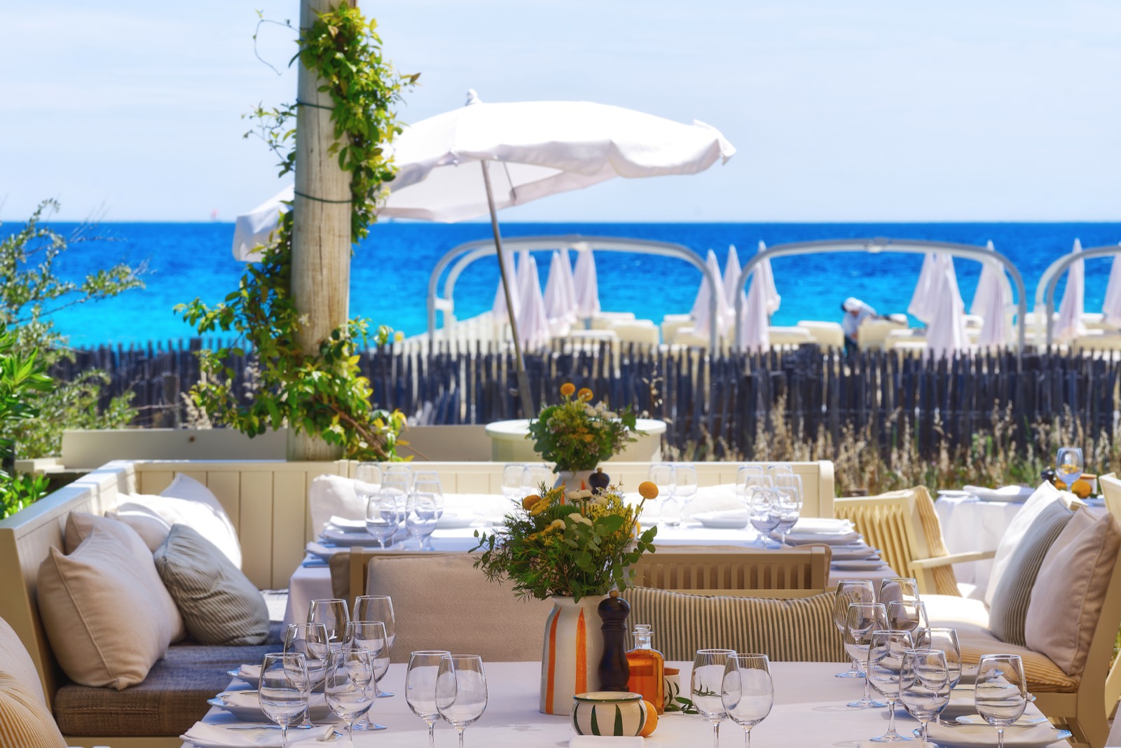 Gedeckter Tisch am Meer unter weißem Sonnenschirm